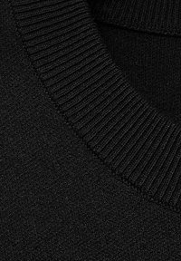 Schwarzer Strickpulloverstoff mit einem gerippten Ausschnitt und glatter Textur, aus der Nahaufnahme hervorgehoben, die die Dichte des Materials zeigt.