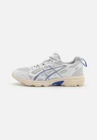 Chaussure de sport blanche avec un dessus en mesh et synthétique, présentant des accents bleus et gris, une semelle rembourrée et une languette à l'arrière.