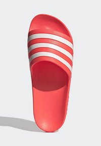 Koraalrode slide sandaal met een textuur bovenkant, voorzien van drie horizontale witte strepen. Open teen ontwerp, zachte binnenvoering en platte zool.