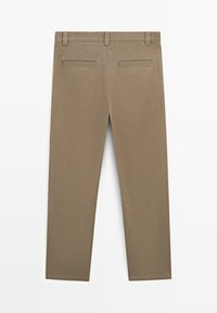 Beżowe bawełniane spodnie o prostym kroju, wyposażone w dwie tylne kieszenie i gładką fakturę. Brak widocznych ozdób czy wzorów.