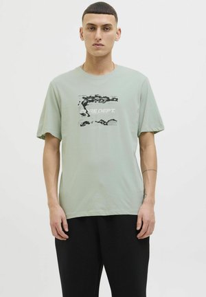 Lys grøn bomulds t-shirt med et sort-hvidt grafisk print på fronten, korte ærmer og en afslappet pasform.