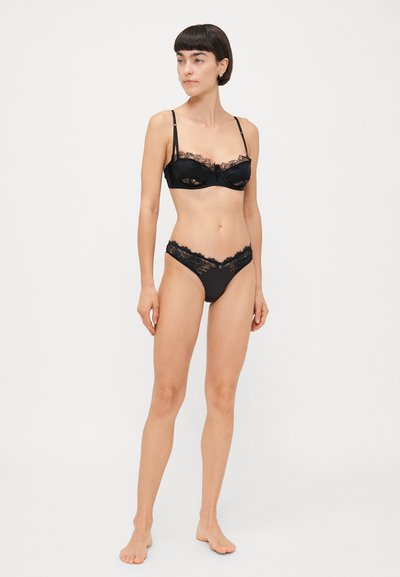 Black lace bra and matching panties set. Bra features underwire, adjustable straps; panties have lace trim and smooth fabric.
