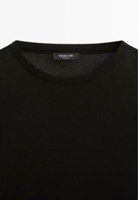 Zwarte katoen t-shirt met een ronde hals, met een zachte textuur. Het label aan de binnenkant van de hals luidt "Massimo Dutti, Made in China."