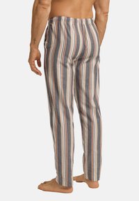 Raidat unipökät harmaana, valkoisena ja ruosteenvärisenä, joissa on joustava vyötärö ja sivutaskut, valmistettu pehmeästä ja hengittävästä kankaasta.