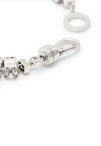 Bracciale in argento con cristalli chiari a forma quadrata, una chiusura arrotondata e un logo inciso. La finitura è in metallo lucido.