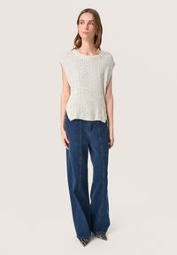 Top grigio chiaro a maglia con texture a coste, scollatura rotonda e maniche a cappuccio, abbinato a pantaloni di jeans scuri a gamba larga e décolleté a fantasia.