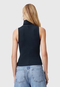 Top sin mangas de color marino con un cuello alto, hecho de tela acanalada. Presenta una silueta ajustada y una costura central en la parte posterior.