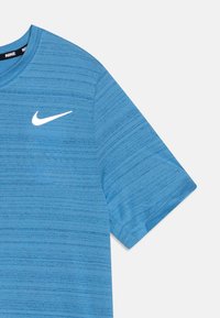 Zila sporta T-kreklu izgatavots no teksturēta auduma, ar apaļu kakla izgriezumu un īsām piedurknēm. Uz krūšu daļas ir balts Nike logo.