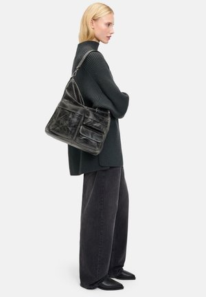 Schwarze Leder-Schultertasche mit mehreren Fächern, runder Form und glatter Textur. Tragen zu einem dunklen Pullover und weit geschnittenen Hosen.