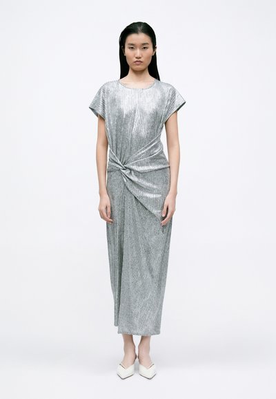 Vestido plateado de longitud a la rodilla con un detalle de nudo retorcido en la cintura. Mangas cortas, textura suave y una silueta elegante y ajustada.