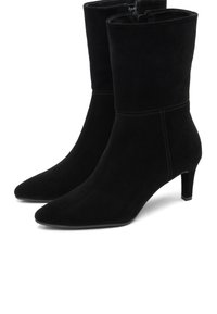 Botas de ante negras de media caña con puntas afiladas, tacones delgados, cremalleras laterales y detalles de costura mínimos.
