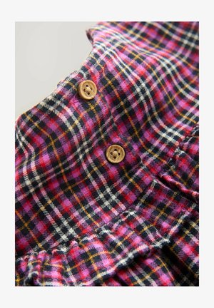 Gekruist stof in roze, zwart en wit met oranje accenten; heeft houten knopen en ruffles langs de onderrand.