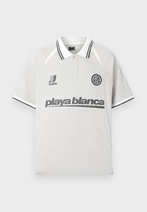 Tricou polo alb cu mâneci scurte, cu accente de dungi negre, un logo „playa blanca” pe piept și două logo-uri mai mici lângă guler.