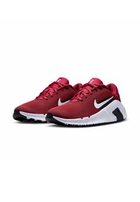 Punaiset verkkomateriaalista valmistetut urheilukengät, joissa on mustia ja valkoisia yksityiskohtia. Ominaisuuksiin kuuluu pehmustettu pohja, teksturoitu päällinen ja silmiinpistävä Nike-logo sivulla.
