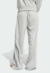 Harmaat urheiluhousut, joissa on rento istuvuus, joustava vyötärö ja hillityt sivuraidat. Valmistettu sileästä, hengittävästä materiaalista.