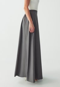 Gray maxi skirt made of soft fabric, featuring a high waistband and pleated design, with a flowy silhouette reaching the ankles.