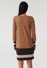 Vestito lavorato a maglia con un corpo marrone e strisce orizzontali a contrasto in crema e marrone scuro. Maniche lunghe con polsini striati.