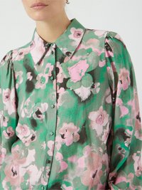 Bloes met bloemenpatroon in groen met roze en zwarte accenten, met een kraag, knoopsluiting aan de voorkant en gerimpelde schouders. Soepele, lichtgewicht stof.
