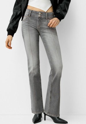 Grijze flared jeans met contrasterende stiksels, een sluiting met twee knopen, frontzakken en een middellange pasvorm. Gestyled met zwarte puntige hakken.