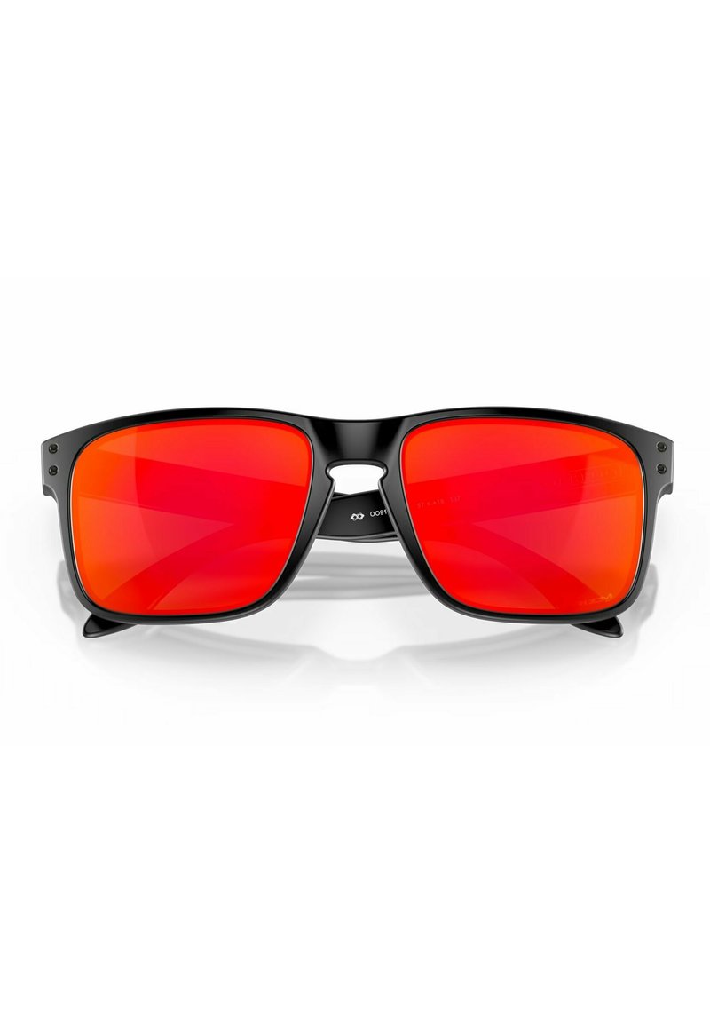Lunettes de soleil à monture noire avec de grandes lentilles miroir rouges. Le design présente un haut plat, de légères courbes aux bords et des accents métalliques.