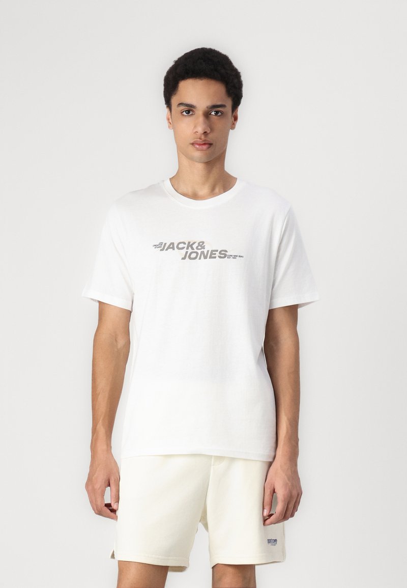 T-shirt en coton blanc avec un grand imprimé graphique « JACK & JONES » gris sur la poitrine. Manches courtes, coupe décontractée, avec une texture lisse.