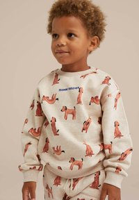 Felpa beige con un divertente motivo di cani in diverse pose, con la scritta "AMICI PER SEMPRE" in blu. Polsini e scollatura a costine.
