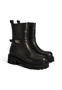 Black leather ankle boots with a smooth finish, featuring a front buckle strap and chunky sole with pronounced treads for grip.