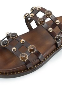 Sandalo in pelle marrone con design a strisce geometriche, accenti trasparenti e dorati, soletta testurizzata e dettagli in oro lungo il bordo della suola.