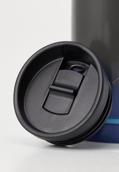 Svart plastlokk med en klaffespytt, med en teksturert overflate, sirkulær form, og en sikkerhetslås mekanisme.