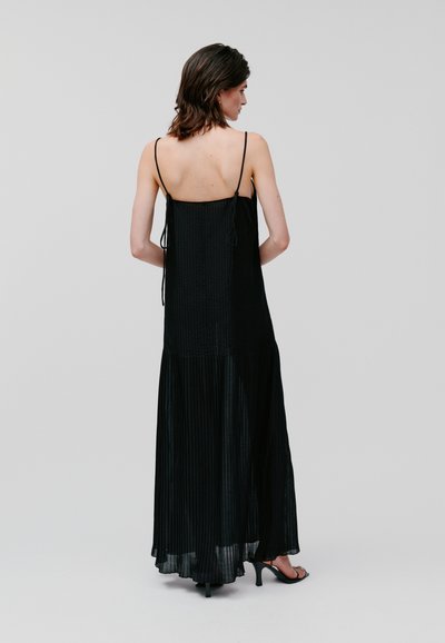 Black maxi dress featuring thin straps, a pleated lower section, and a smooth upper fabric with drawstring details at the back.