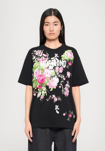 T-shirt en coton noir avec une broderie florale vibrante en rose et vert, avec une marque blanche sur le devant, des manches courtes et une coupe décontractée.