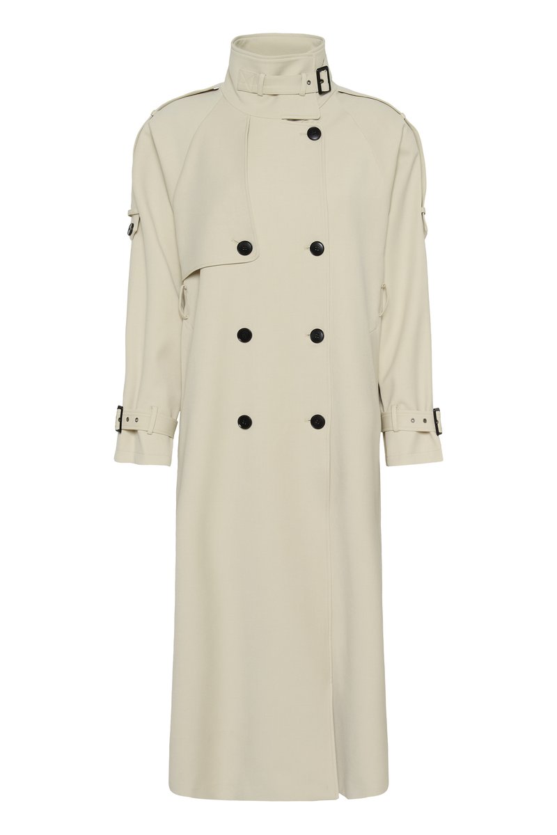 Trench-coat long beige avec col montant, boutons noirs double boutonnage, poignets ceinturés et détails de pattes de manche.