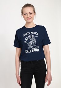 Námořnická modrá bavlněná trička s bílým grafickým textem "Santa Monica", ilustrací tygra a nápisem "California" v tučném písmu.