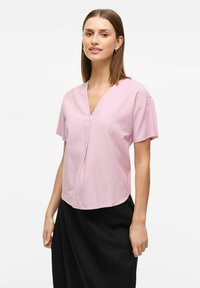 Kortärmad V-ringad rosa blus i lätt tyg med avslappnad passform, med en central veckning och rundad nederkant.