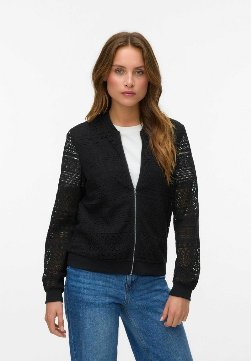Zwarte kant bomberjack met een ritssluiting aan de voorkant, ribbelmanchetten en een volledig zwarte body; voorzien van ingewikkeld patroon kantpanelen op de mouwen.