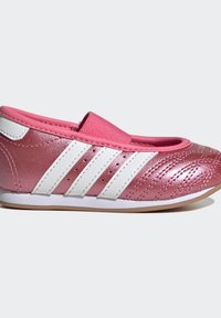 Chaussure rose brillante enfant à enfiler avec des rayures blanches, bande élastique sur le dessus et détails cousus à l’orteil, vue de côté sur un fond clair.