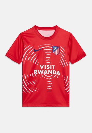 Camiseta deportiva roja de manga corta con patrón circular de ondas blancas, logo de Nike, escudo del Atlético de Madrid y texto "Visit Rwanda" en la parte delantera.
