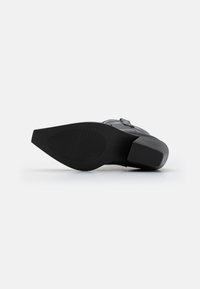 Black rubber sole of a shoe, featuring a smooth finish and textured grip pattern. The shoe has a clean design with minimal accents.