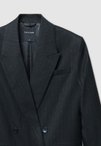Blazer nero su misura con motivo a righe sottili, revers a punta, chiusura a doppio bottone e tasca frontale. Realizzato in tessuto liscio, design strutturato.