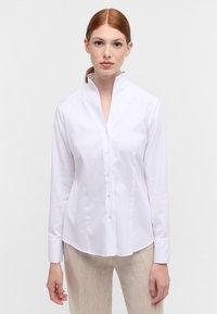 White long-sleeve shirt with a high collar, button front closure, and smooth texture. Tailored fit with subtle textured pattern.