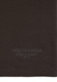 Tmavě hnědé bavlněné tričko s hladkou texturou. Obsahuje vyšívané logo "Chelsea Peers Established 2012" blízko lemu.