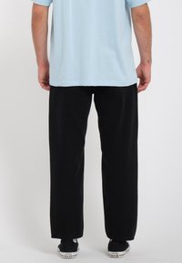 Zwarte denim broek met een rechte pasvorm, gecombineerd met een lichtblauw T-shirt. Kenmerkt zich door het klassieke vijf-pocket ontwerp en minimalistische sneakers.
