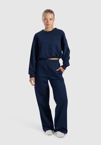 Marineblauwe cropped sweatshirt met elastische zoom en bijpassende hooggetailleerde sweatpants met zijzakken en een elastische tailleband.