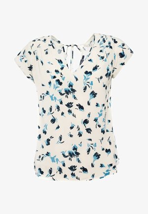 Blouse crème à motif floral bleu et noir, manches courtes, col en V avec lien à nouer dans le dos.