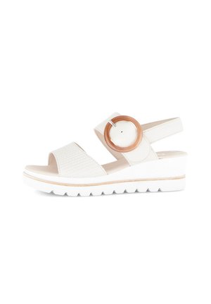 White wedge sandals featuring a textured strap, circular wooden accent, and a rubber sole with a contoured shape and slight platform.