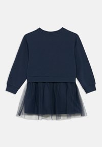 Tumši zila kokvilnas maisījuma kleita ar garām piedurknēm un kārtainu tilla svārku; tai ir apaļa kakla izgriezums un elastīgas aproces.