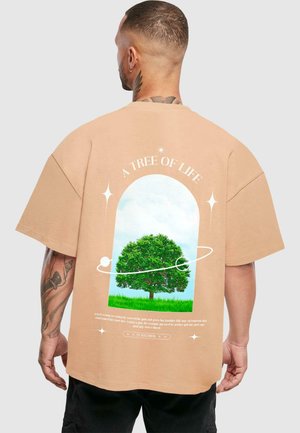 Lys beiges oversized t-skjorte med grafikk av et tre i en rammedesign med tekst, stjerner og en sirkulær kontur på baksiden.
