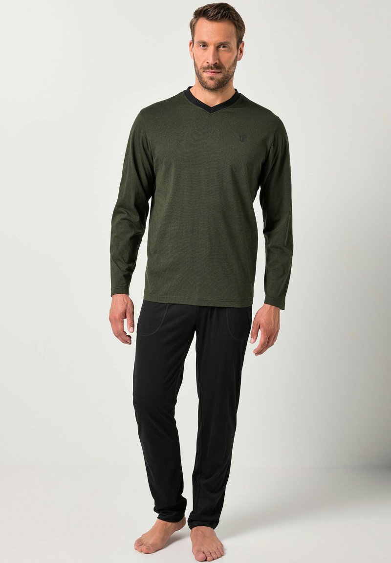 Camisa de manga larga a rayas verdes con cuello en V negro, combinada con pantalones negros que cuentan con bolsillos laterales y una textura suave.