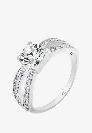 Inel de argint cu o piatră mare și rotundă, clară, la centru, flancată de pietre mici, clare, dispuse într-un setting canal pe bandă.