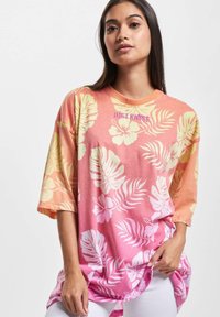 Oversized, short-sleeve t-shirt in gradient pink and orange with white floral and leaf patterns. Features "JUST RHYSE" text in purple.